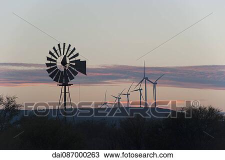 Stock Image - Tranquil view of an old-fashioned windmill and modern wind turbines against a twilit sky. Fotosearch