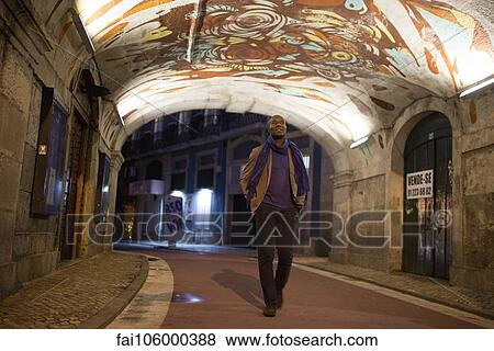 Stock Photo - Traveler strolling through graffitied walkway. Fotosearch