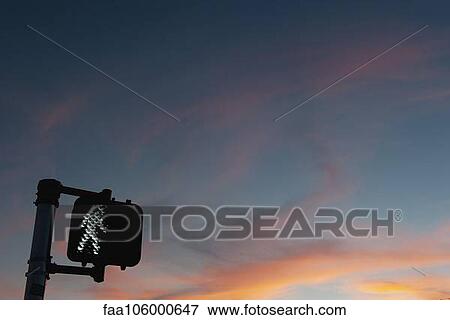 Stock Photo - Walk signal with sunset in the background. Fotosearch