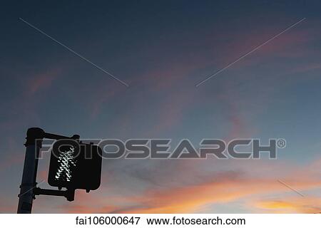 Stock Photo - Walk signal with sunset in the background. Fotosearch