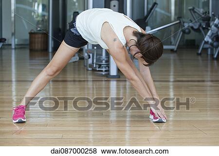 Woman bending over to touch toes in health club View Large Photo Image Stock Photo - Woman bending over to touch toes in health club. Fotosearch