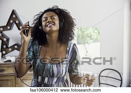Woman dancing while listening to music playing on smartphone View Large Photo Image Stock Image - Woman dancing while listening to music playing on smartphone. Fotosearch