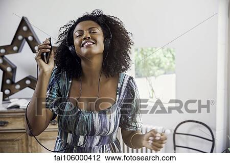 Woman dancing while listening to music playing on smartphone View Large Photo Image Stock Image - Woman dancing while listening to music playing on smartphone. Fotosearch