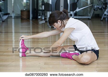 Woman doing stretches on the floor in health club View Large Photo Image Stock Image - Woman doing stretches on the floor in health club. Fotosearch