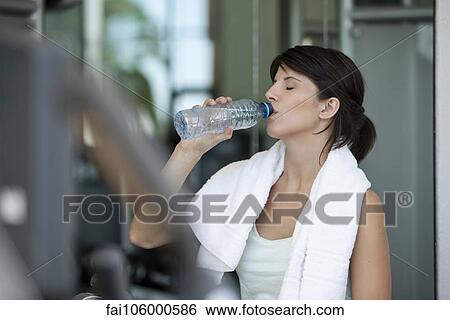 Woman drinking bottled water after a workout View Large Photo Image Stock Photograph - Woman drinking bottled water after a workout. Fotosearch