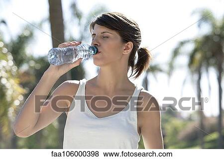 Woman drinking bottled water outdoors View Large Photo Image Stock Photo - Woman drinking bottled water outdoors. Fotosearch