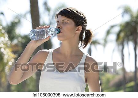 Woman drinking bottled water outdoors View Large Photo Image Stock Photo - Woman drinking bottled water outdoors. Fotosearch