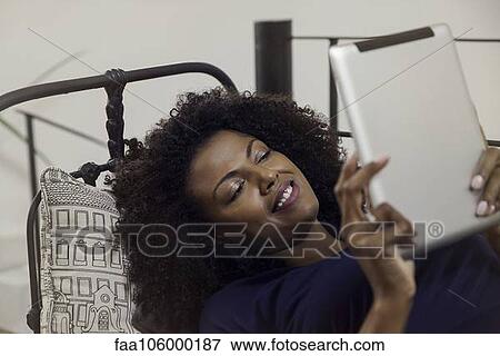 Woman enjoying book displayed on e-reader View Large Photo Image Stock Photo - Woman enjoying book displayed on e-reader. Fotosearch