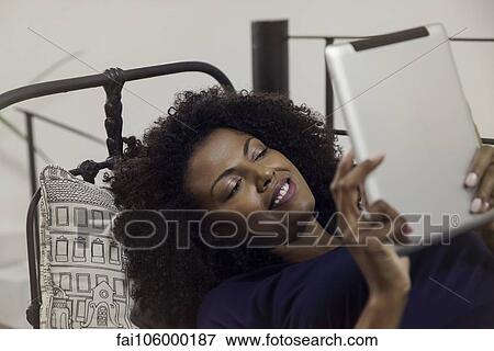 Woman enjoying book displayed on e-reader View Large Photo Image Stock Photo - Woman enjoying book displayed on e-reader. Fotosearch