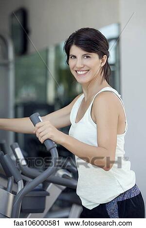 Woman exercising in fitness club, smiling cheerfully View Large Photo Image Stock Image - Woman exercising in fitness club, smiling cheerfully. Fotosearch