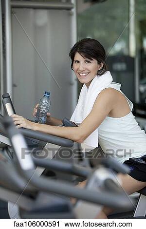 Woman exercising in fitness club with water bottle in hand View Large Photo Image Stock Image - Woman exercising in fitness club with water bottle in hand. Fotosearch