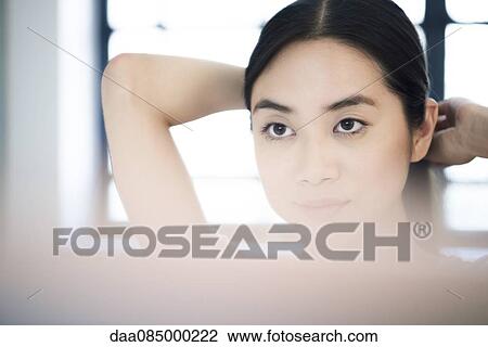 Woman fixing her hair in mirror View Large Photo Image Stock Image - Woman fixing her hair in mirror. Fotosearch