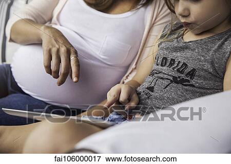 Woman helping daughter using educational app on digital tablet View Large Photo Image Stock Photo - Woman helping daughter using educational app on digital tablet. Fotosearch
