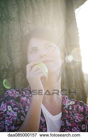 Woman holding apple, looking up dreamily, portrait View Large Photo Image Stock Photo - Woman holding apple, looking up dreamily, portrait. Fotosearch