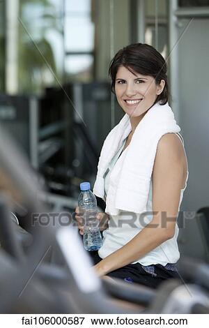 Woman holding bottled water and smiling after a workout View Large Photo Image Stock Photo - Woman holding bottled water and smiling after a workout. Fotosearch