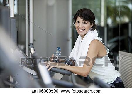 Stock Image - Woman hydrating after a workout, smiling. Fotosearch