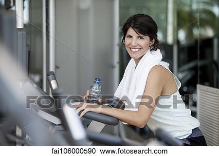 Stock Image - Woman hydrating after a workout, smiling. Fotosearch
