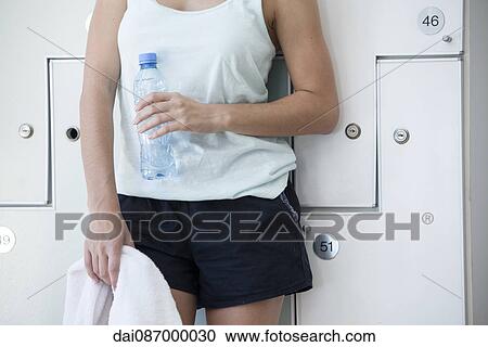 Woman leaning against lockers, with towel and bottled water, cropped View Large Photo Image Stock Image - Woman leaning against lockers, with towel and bottled water, cropped. Fotosearch