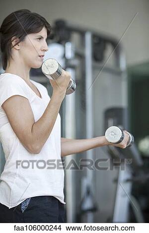 Woman lifting weights in gym View Large Photo Image Picture - Woman lifting weights in gym. Fotosearch
