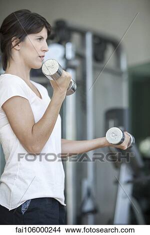 Woman lifting weights in gym View Large Photo Image Picture - Woman lifting weights in gym. Fotosearch