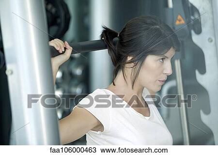 Stock Image - Woman lifting weights in gym. Fotosearch