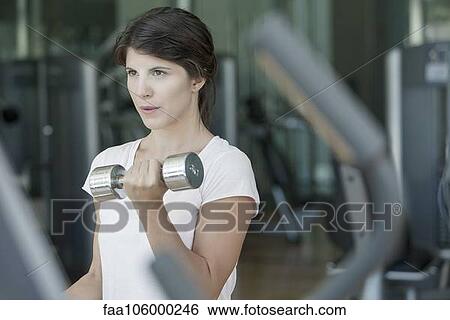 Woman lifting weights in gym View Large Photo Image Stock Photograph - Woman lifting weights in gym. Fotosearch