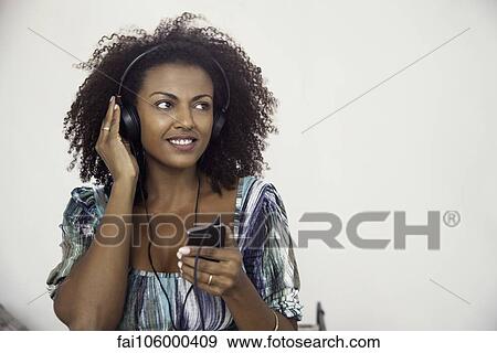 Stock Photo - Woman listening to music playing on mp3 player. Fotosearch