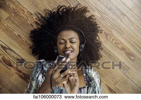 Stock Image - Woman listening to music playing on smartphone. Fotosearch