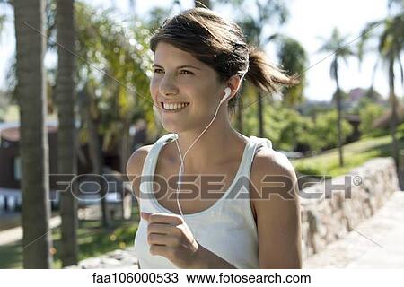 Woman listening to music while jogging View Large Photo Image Stock Image - Woman listening to music while jogging. Fotosearch