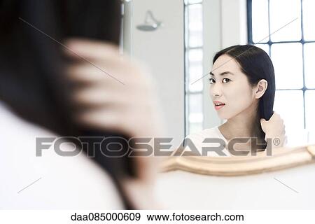 Woman looking in mirror, fixing her hair View Large Photo Image Stock Photo - Woman looking in mirror, fixing her hair. Fotosearch
