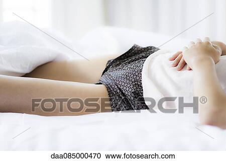 Woman lying in bed with hands on stomach, cropped View Large Photo Image Stock Image - Woman lying in bed with hands on stomach, cropped. Fotosearch