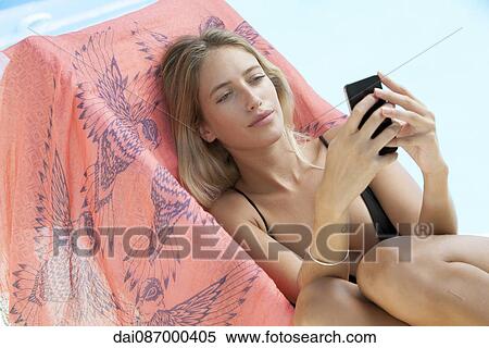Woman relaxing by pool, sending text message View Large Photo Image Stock Photography - Woman relaxing by pool, sending text message. Fotosearch