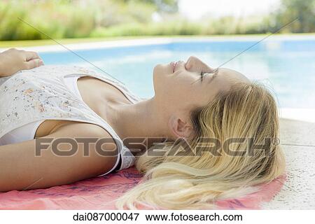 Woman relaxing by pool with eyes closed View Large Photo Image Stock Photo - Woman relaxing by pool with eyes closed. Fotosearch