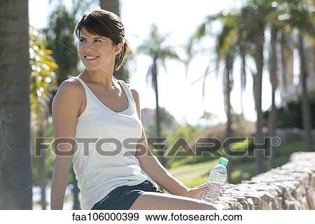 Woman relaxing in park with bottle of water View Large Photo Image Stock Photo - Woman relaxing in park with bottle of water. Fotosearch