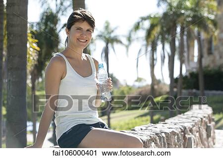 Woman relaxing in park with bottled water, portrait View Large Photo Image Stock Image - Woman relaxing in park with bottled water, portrait. Fotosearch