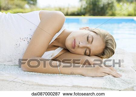 Woman resting at poolside with eyes closed View Large Photo Image Stock Photo - Woman resting at poolside with eyes closed. Fotosearch