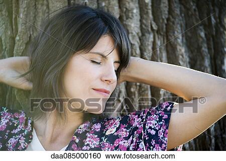 Woman resting head on tree trunk, eyes closed View Large Photo Image Stock Image - Woman resting head on tree trunk, eyes closed. Fotosearch