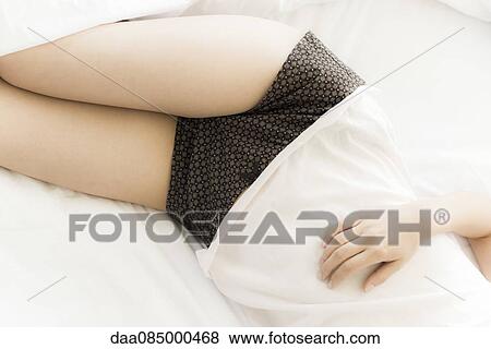 Woman resting on bed, mid section View Large Photo Image Stock Photo - Woman resting on bed, mid section. Fotosearch
