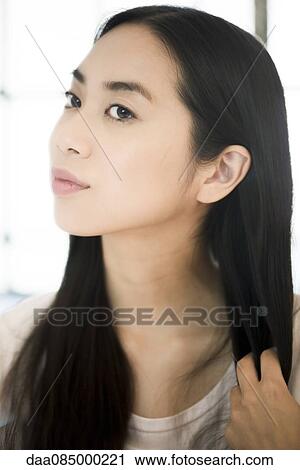 Stock Image - Woman running fingers through ends of hair. Fotosearch