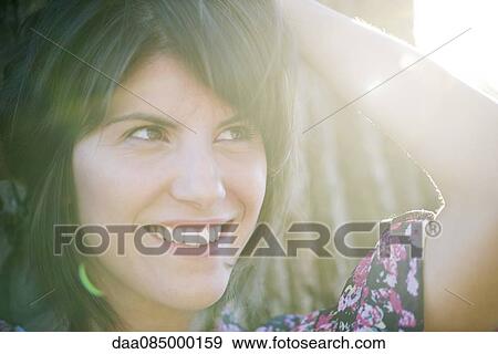 Woman smiling dreamily outdoors, portrait View Large Photo Image Stock Photo - Woman smiling dreamily outdoors, portrait. Fotosearch