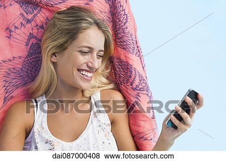 Woman streaming video on smartphone while lounging by pool View Large Photo Image Stock Photo - Woman streaming video on smartphone while lounging by pool. Fotosearch