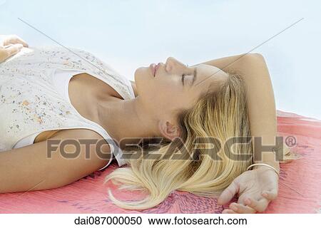 Stock Image - Woman sunbathing at poolside. Fotosearch