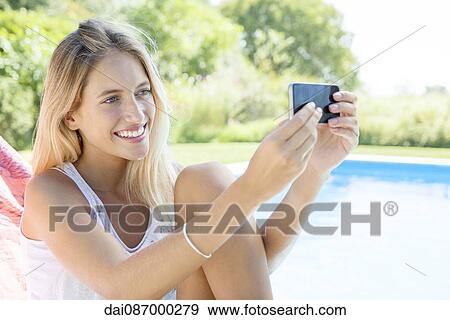 Woman taking a selfie by poolside with smartphone View Large Photo Image Stock Photo - Woman taking a selfie by poolside with smartphone. Fotosearch