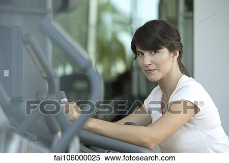 Stock Photography - Woman using exercise machine in health club. Fotosearch