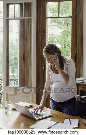 Woman using laptop computer and making phone call View Large Photo Image Stock Photography - Woman using laptop computer and making phone call. Fotosearch
