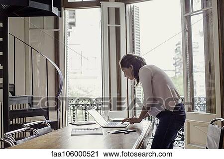 Stock Image - Woman using laptop computer at home. Fotosearch