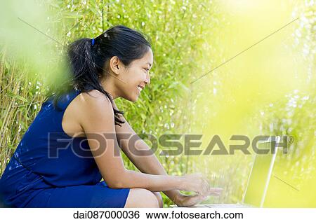Stock Photograph - Woman using laptop computer outdoors. Fotosearch