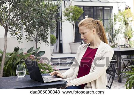 Woman using laptop in hotel courtyard View Large Photo Image Stock Photo - Woman using laptop in hotel courtyard. Fotosearch