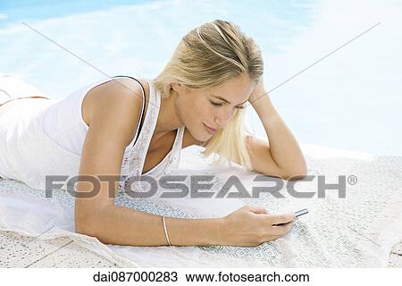 Woman using smartphone while relaxing at poolside, portrait View Large Photo Image Stock Image - Woman using smartphone while relaxing at poolside, portrait. Fotosearch