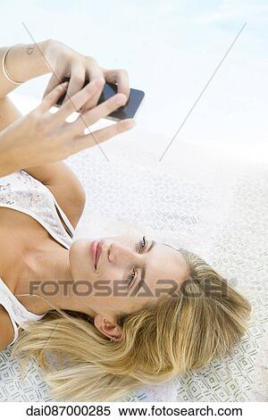 Woman using smartphone while relaxing at poolside, portrait View Large Photo Image Stock Photography - Woman using smartphone while relaxing at poolside, portrait. Fotosearch